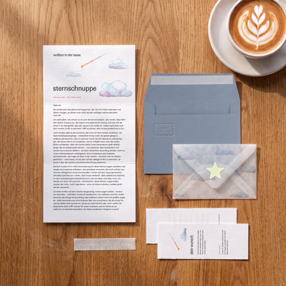 wolken in der tasse, Brief Oktober „sternschnuppe“ auf einem Eichentisch, graublauer Umschlag mit Prägung, Transparentumschlag mit Wolkendruck und Leuchtstern, Wunschkarte, Cappuccino